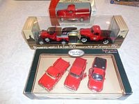 Image showing the six die cast pickup trucks in their original boxes with clear display windows. Includes three red pickup trucks in a frame, a 1929 Ford Model A tow truck towing a 1952 Chevrolet pickup, and a 1940 Ford pickup truck.