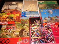 Seven jigsaw puzzle boxes arranged showing their cover images illustrating the variety in the lot.