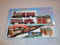Boxed Christmas train set with Dickensville Express branding and contents visible through plastic window showing locomotives and train cars.
