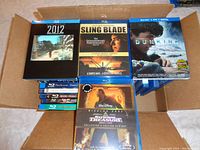 Top view of box showing stack of Blu-ray movies including 2012, Sling Blade, Dunkirk, and National Treasure.