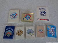 Seven sealed and opened boxed card sets and postcards from Toronto Blue Jays championship years displayed flat on surface.
