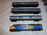 Top view showing diesel engine and three passenger cars with VIA Rail blue and yellow livery on top side.