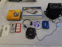 Five vintage audio devices including boxed Citizen Slim Cassette Recorder, boxed Panasonic RQ-V65 stereo radio cassette player, Realistic microcassette recorder with manual and blank tapes, blue Sanyo walkman type cassette player, Panasonic CD player with headphones and carrying case.