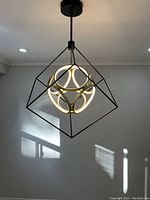 Large modern geometric LED chandelier hanging from ceiling with cube frame and illuminated spherical inner design showing LED light elements glowing