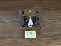 Front view of the wooden pipe stand with four pipes inserted, showing the slots holding pipe stems and circular bases holding pipe bowls.