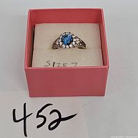 Top angle of sterling silver ring with blue and clear cubic zirconia stones in red box showing size 7 tag