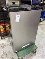 Front view of the compact Frigidaire refrigerator showing stainless steel door and top handle area with brand label.