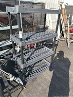 Full view of the assembled black plastic 4-tier shelf unit on wheels outdoors.
