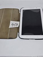 Samsung Galaxy Note 8 tablet inside a protective cover, cover interior is beige with visible wear and some discoloration, tablet screen off and showing ripple effect on screen.