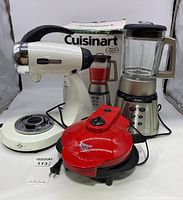 View of Cuisinart blender with original box, vintage Sunbeam mixer, and red hot plate all together.