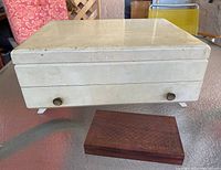 Closed view of large white vanity chest and small wooden keepsake box on tabletop.
