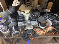 Photo showing two Minolta cameras, various lenses including Vivitar and Konica Maxumars 50mm lens in original box.