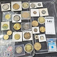 Top-down view of the full collection showing coins and medallions arranged on two trays with some in protective holders and sleeves.