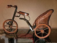 Side-angle photo showing the full wagon with metal frame, wooden wheels, and wicker basket seat
