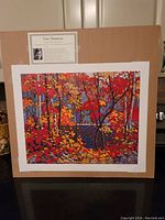Full front view of the lithograph showing the colorful autumn forest scene and mounted biographical card on cardboard backing.