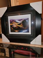 Front view of professionally framed fine art print with black frame and black matting, showing colorful landscape of hills and lake titled 'Grace Lake'.