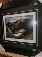 Close-up of the framed print showing the colorful mountain landscape and signature