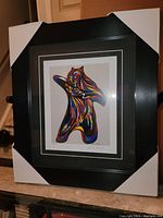 Photo showing the professionally framed colorful bear print with visible protective corners on the frame.