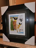 Full view of the framed Maud Lewis fine art print titled "Two Deer" with protective corner coverings.