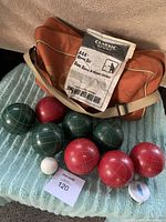 Complete Bocce ball set showing four green balls, four red balls, one white pallino, orange carrying bag, and instruction sheet.