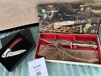 Wide shot of both knives in original boxes showing condition and packaging.