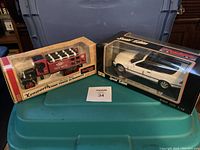 Photo showing two die-cast models in original boxes: 1925 Kenworth Stake Truck and 1993 BMW 325i Convertible, placed on plastic container.
