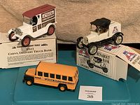 Lot containing 1923 Chevy panel delivery truck bank, runabout truck model, and yellow school bus toy on a blue surface.