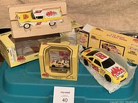 Three boxed Mac Tools racing die-cast collectibles: #32 Tektronics car, #28 limited edition car, #28 die-cast bank.