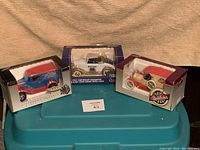 Three die-cast collectible model cars in original boxes including 1937 Chevy Roadster, Model A Ford, and 1916 Studebaker