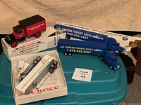 All four items together with original boxes: red 1931 Hawkeye truck bank, two blue Harbor Freight Freightliner trucks, and Mac Tools Winross Freightliner MTS164 truck.