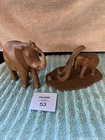 Photo of both hand carved wooden elephant figurines side by side on blue towel