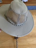 Front and side views of the light tan men's sun hat showing wide brim, mesh ventilation panels on crown, and adjustable chin strap with toggle