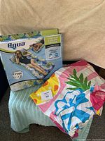 New Aqua Contour Cooling Lounge inflatable pool float partially inflated next to the original box.