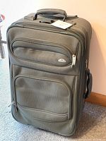 Front view of army green Samsonite carry-on suitcase showing exterior pockets and textured fabric