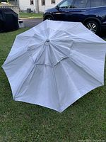 Top view of open light gray umbrella canopy laid on grass.