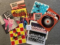 All roller game programs and two black and white team photos laid out flat on carpet