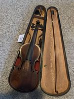 Violin inside open case showing full body and bow secured in case.