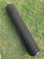 Roll of plastic chicken wire fence in black color laid on grass