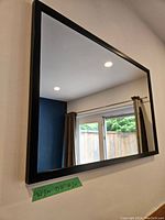 Side angle view of black framed rectangular mirror mounted on wall, showing the depth and frame thickness.