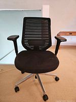 Front view of chair showing mesh back, padded seat and aluminum base with casters