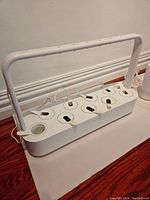 Front view showing rectangular base with nine pod slots and central power light, white plastic construction, dust present