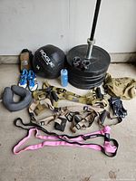 Full view of all items laid out in garage: barbell, plates, med ball, trainers, shoes, gloves, bands, collars, water bottle