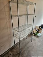 Front angle view of 5-shelf metal wire storage unit against a wall in a garage showing full height and width.