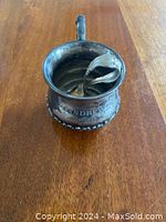 Silver mug with inscription 'Andrew May 1909' and decorative handle, showing age-related tarnishing