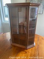 Front view of the mahogany hanging display case with two glass doors closed, showing its traditional polished wood and brass trimmed design.