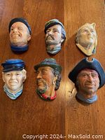 Overview of six hand-painted Bossons chalkware head plaques on wooden table