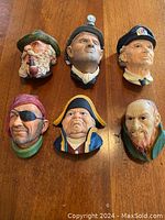 Six Bosson head plaques laid out on wood surface (includes excluded Fagin character)