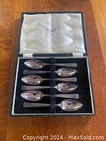 Boxed set of 6 silver tea spoons in leather bound felt lined case. Shows the spoons resting inside the box with satin lid lining.