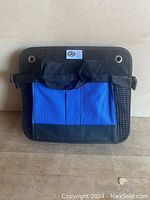 Front view of closed CAA roadside storage bag in black and blue colors with handles and grommets.