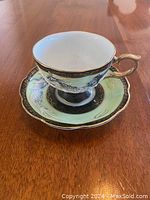 Cup and saucer set showing embossed dragon design and gold accents
